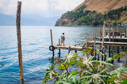 Santa Cruz la Laguna, Guatemala - 29 March 2018: Man waiting at wooden dock along lake Atitlan at the coast