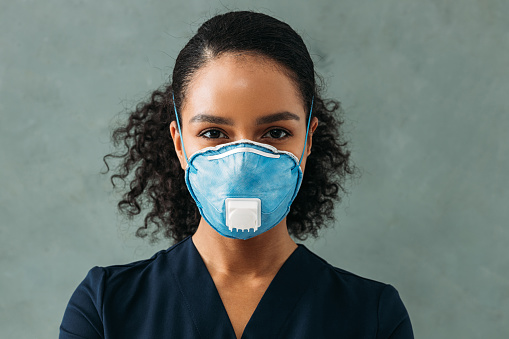 Portrait of a young nurse wearing respirator looking straight of a camera