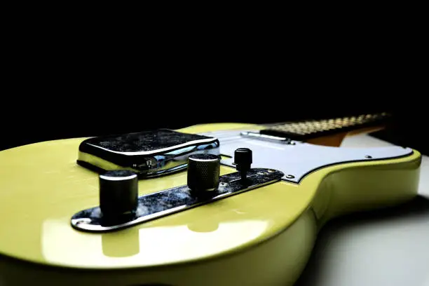 Vintage yellow - blond finish telecaster guitar on a black background - close up
