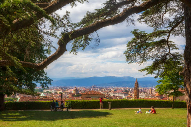 Tourist explore the grounds of the Boboli Gardens, with the cityscape providing a beautiful background during a summer day. stock photo