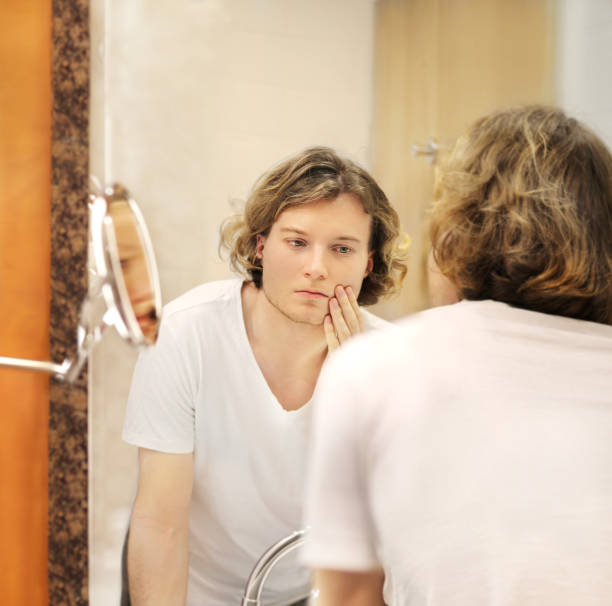 istock Applying the cream.young man looking in the mirror 1294000296