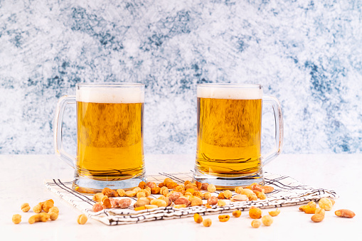 Two glasses of beer with peanuts