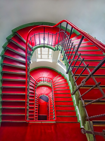 A winding historical staircase with red linoleum lining