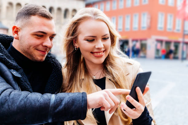 istock Young couple happily looking at a cell phone and he shows her something 1294011785