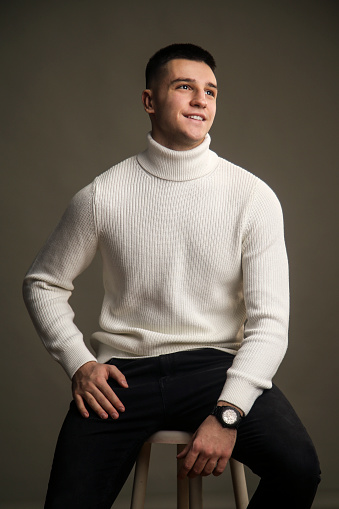 Young male fashion model posing wearing a turtleneck in a studio. About 20 years old, Caucasian man.