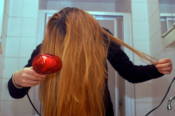 istock young woman blow drying her long hair 1294014848