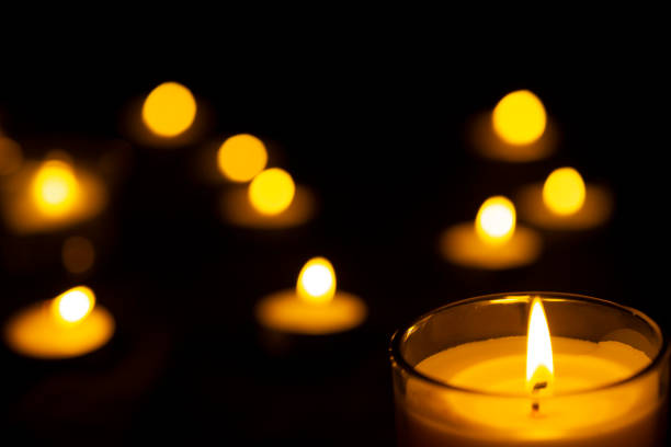 istock Burning candles and yellow light spots with black background 1294017343