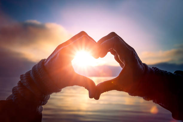 istock Heart shaped from hands with sunlight at the lake 1294021307