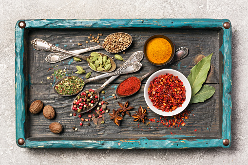 Top view of mix bright spices as ingredient for healthy food on vintage wooden turquoise tray and gray concrete background