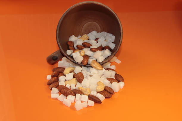 Cashew nuts, almonds and coconut in a mug on an orange background