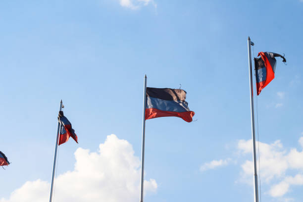 bandeira dnr em um fundo de céu azul. uma bandeira desgrenhada. - donetsk oblast - fotografias e filmes do acervo