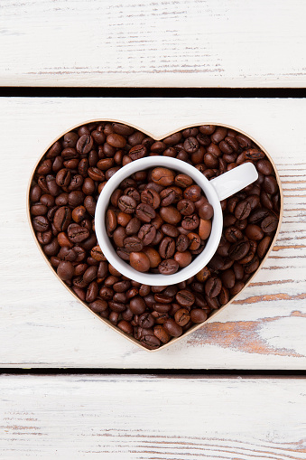 Valentines day background from coffee beans. Heart shape form and cup.