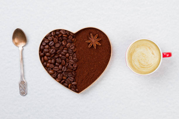 Decorative coffee heart with teaspoon and coffee mug with foam.