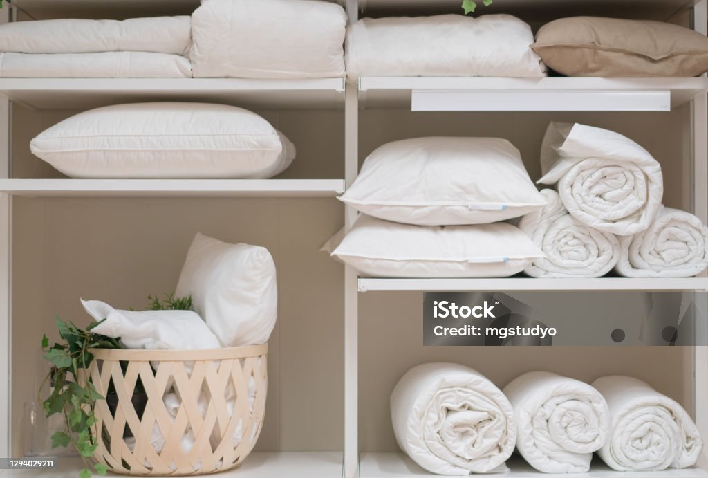 Various household items such as pillows and quilts standing in the white cupboard. Various household items such as pillows and quilts standing in the white cupboard in the laundry room. Closet Stock Photo