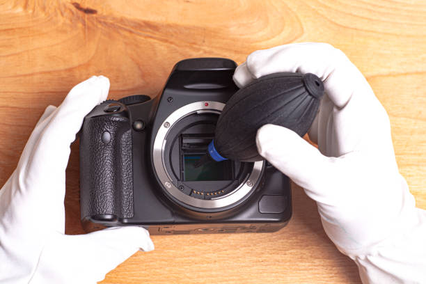 istock Hand wearing white gloves cleaning camera with air dust blower. 1294031362