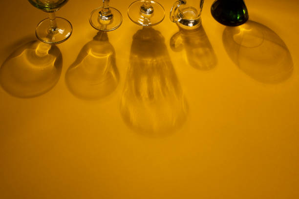 Glasses with strong shadows on yellow background. Copy space. Food concept. High view angle.