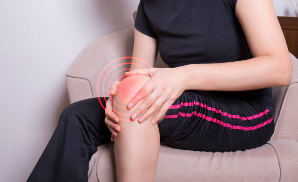 istock woman holding her aching knee 1294039357