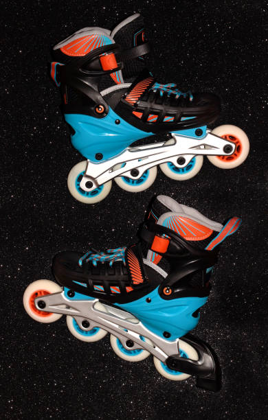 istock Roller skates on a black background. Rollers are black and blue with orange. 1294039499