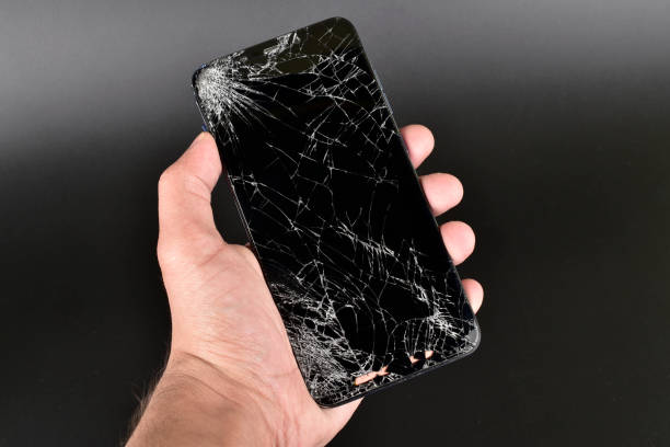 istock Broken smartphone in hand on dark background 1294042125