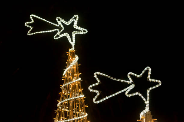 Two Christmas trees, tree toppers, street lights at night, star shape, townsquare, Santiago de Compostela, A Coruña, Galicia, Spain.