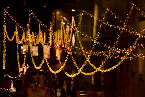 Street light Christmas decorations, rows of LED lights over Christmas market, , busy pedestrian street in old town Santiago de Compostela, Galicia, Spain.