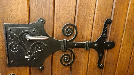 Old metal wrought iron lock in wooden doors. The photo is in selective focus.
