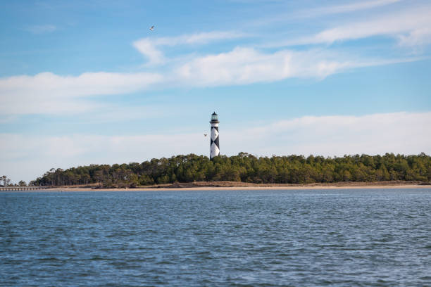 Cape Lookout Lighthouse, North Carolina The Cape Lookout Lighthouse at Cape Lookout, North Carolina, viewed from the water. bodie island stock pictures, royalty-free photos & images