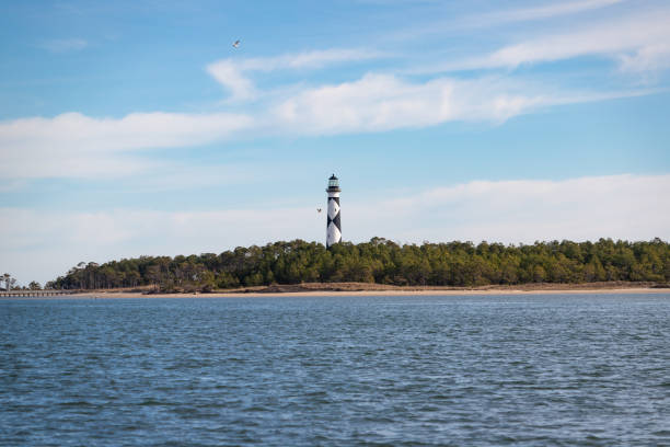 Cape Lookout Lighthouse, North Carolina The Cape Lookout Lighthouse at Cape Lookout, North Carolina, viewed from the water. headland stock pictures, royalty-free photos & images