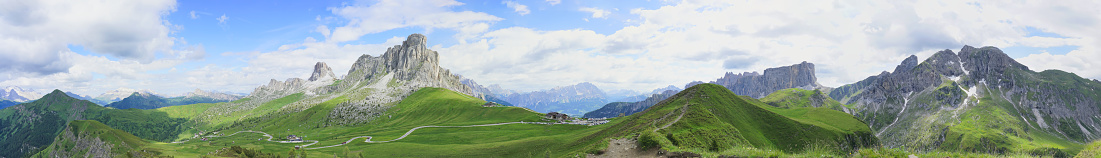 Panorama of the Italian Alps under blue sky and white clouds, beautiful mountain scenery in summer