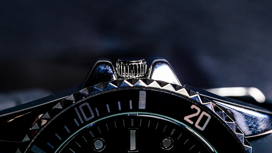 Close-up of the crown of a black and chrome colored men's wristwatch.