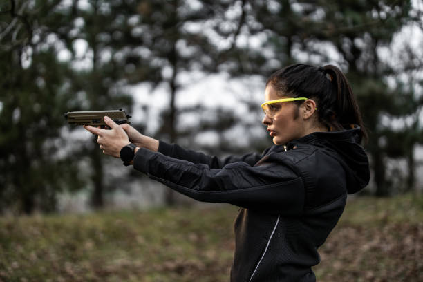 Young woman aiming and practising shooting from pistol at shooting range