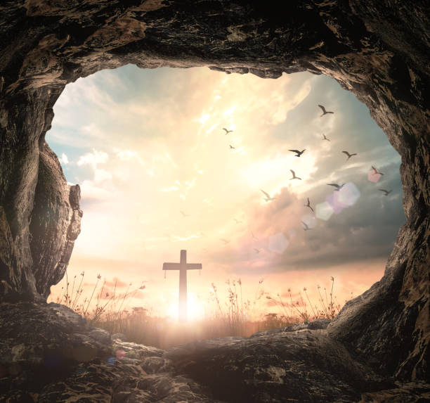istock Empty tomb stone with cross on meadow sunrise 1294071204