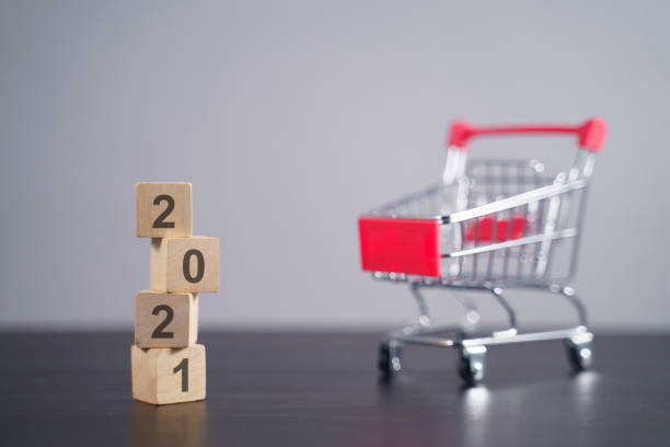 istock Text 2021 on wooden cube with shopping cart. 1294087850