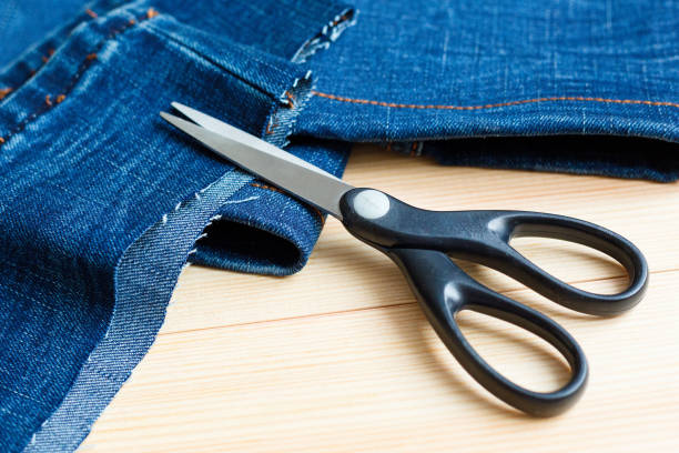 istock Scissors on pieces of cut denim. Wood background 1294089340