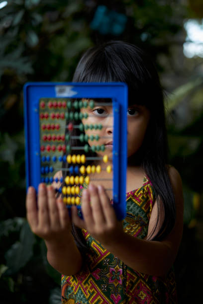 Cute little girl learn counting and Mathematics using abacus at park stock photo