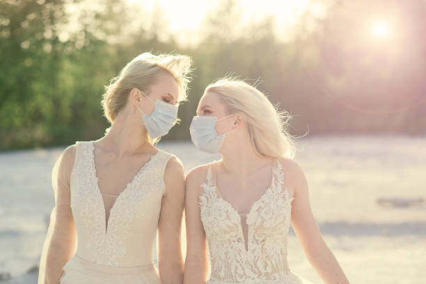 Lesbian couple wedding, wear masks to prevent epidemic COVID-19 Lesbian couple wedding on white sand, wear masks to prevent epidemic COVID-19 gay wedding kiss stock pictures, royalty-free photos & images