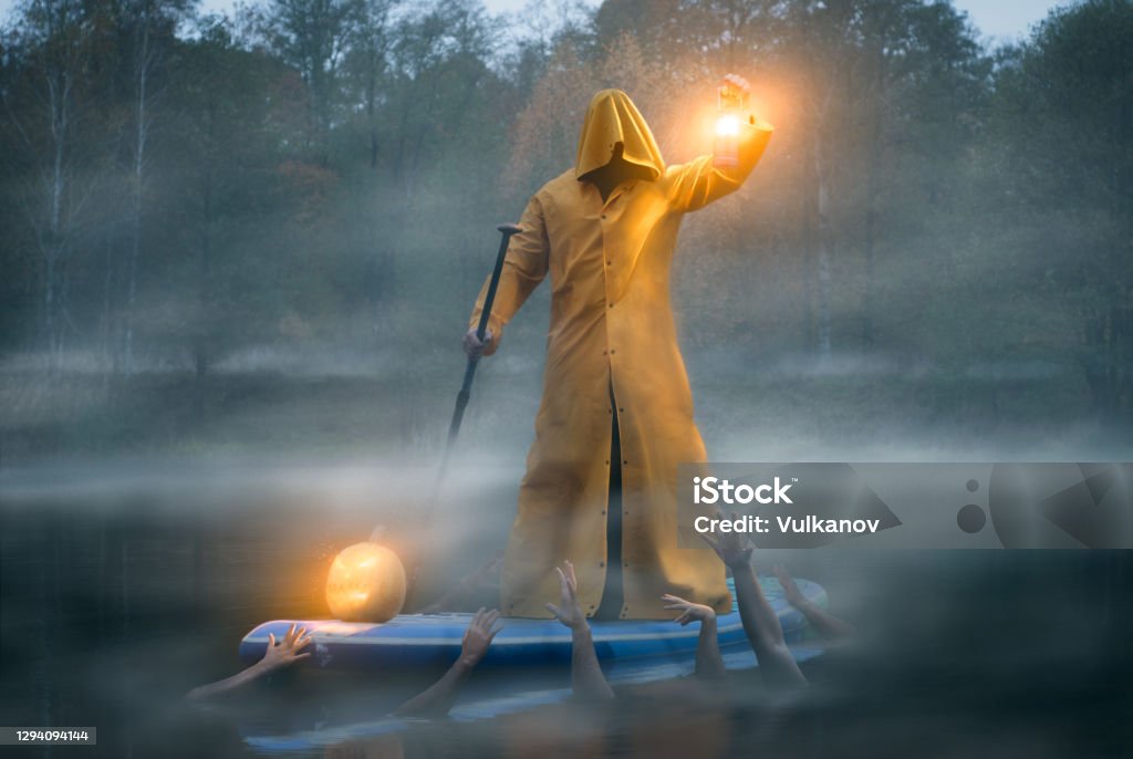 man on a paddle board in a yellow raincoat, photo art charon and the river Styx man on a paddle board in a yellow raincoat, photo art charon and the river Styx. High quality photo Adult Stock Photo