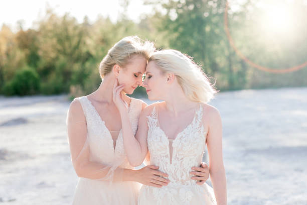 Two brides women in white dress with blonde hair hugging each other Two brides women in white dress with blonde hair hugging each other, lesbian wedding gay long hair stock pictures, royalty-free photos & images