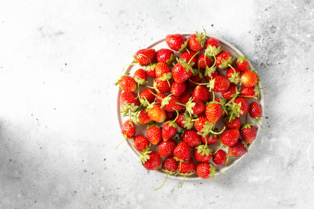 istock Strawberry. Strawberries in a white ceramic plate on a light gray background. Lots of strawberries. Top view with copyspace 1294106046