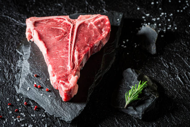 Raw and red steak with salt and pepper Raw and red steak with salt and pepper on black rock porterhouse steak stock pictures, royalty-free photos & images