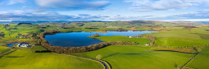 The view from a drone of an loch in south west Scotland on a calm bright sunny day.\nThe panorama was created by merging several images together.