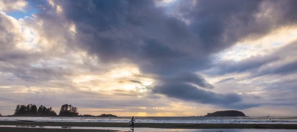 istock Evening sky at Chesterman Beach, with a surfer walking along the beach, his reflection seen in the water 1294119953
