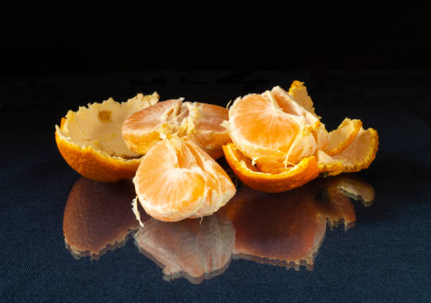 istock Segments of the tangerine on glass table with reflection. 1294122826