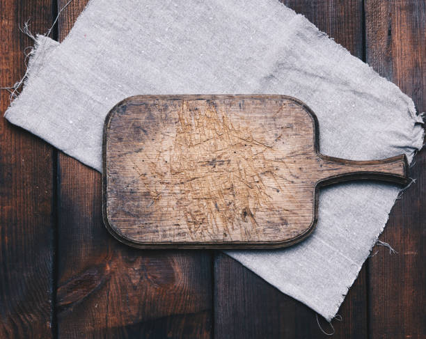 istock old brown rectangular wooden kitchen cutting board and gray linen napkin on the table 1294122854