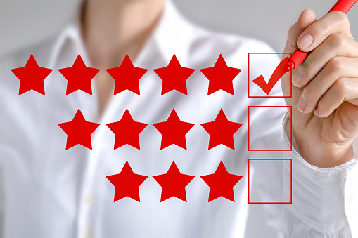Business woman checking to five star service rating symbol with copy space. Hand putting check mark with red marker on five star rating.