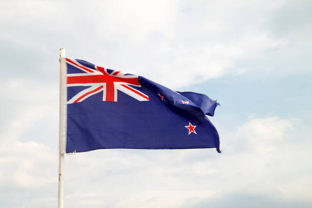 istock New Zealand flag on a blue sky with clouds background 1294122955