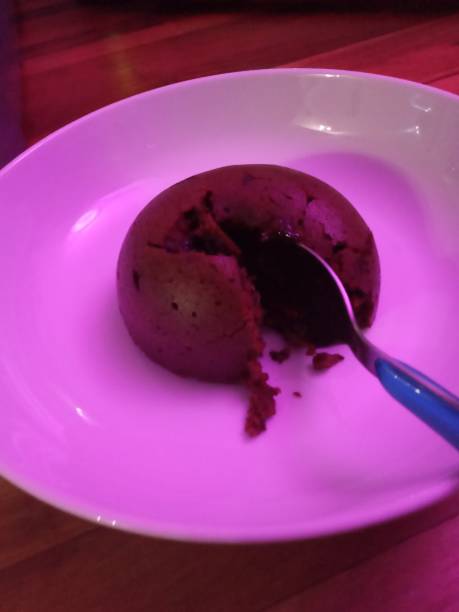 Chocolate Bombe dessert plated A chocolate sponge bombe desert in pink light. plated chocolate dessert stock pictures, royalty-free photos & images