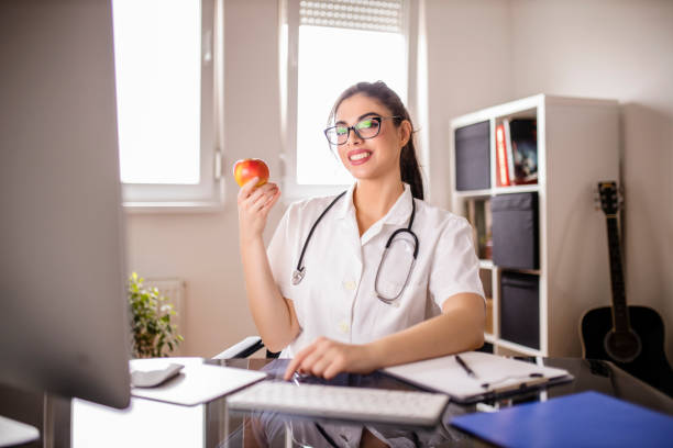 istock Female doctor taking a break and eating apple at her office 1294124843
