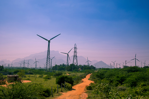 Beautiful view of Windmills or Wind Turbines farm in Nagercoil, South India. With a colorful sky and mountains as a background.