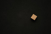 Single wooden cube on black background with a copy space. Flat lay view concept.
